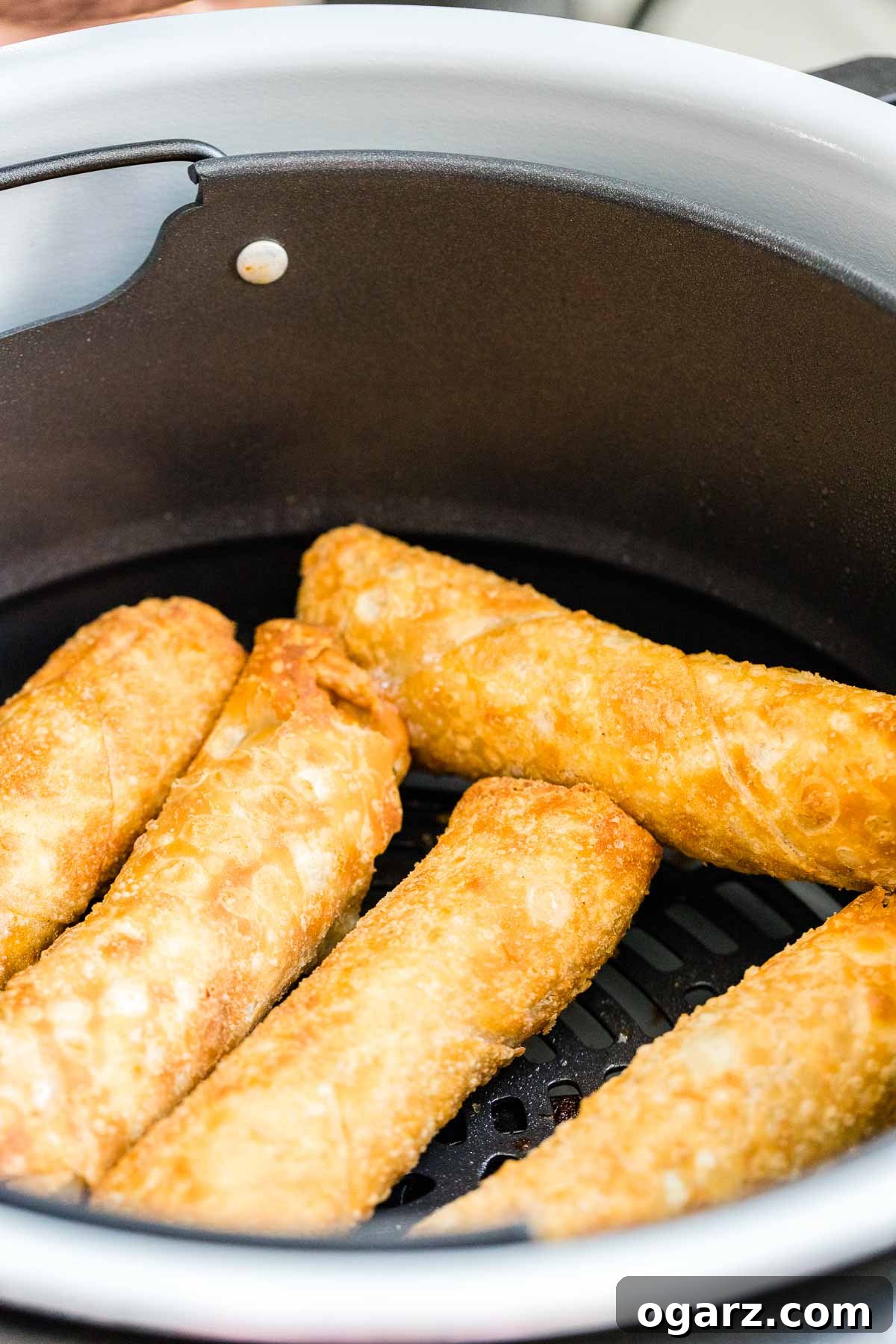 Crispy Air Fryer Egg Rolls 3 Frozen Egg Rolls neatly arranged in an Air Fryer basket, ready for cooking.