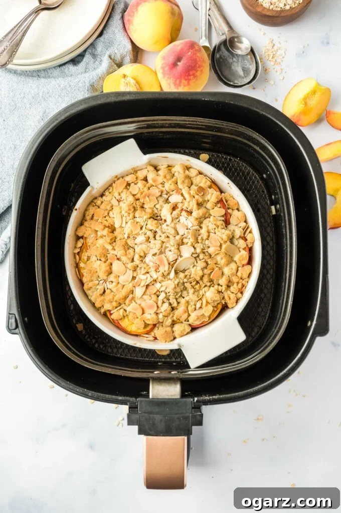 Golden Air Fryer Peach Delight 6 A cooked peach crumble, golden brown and bubbly, in a baking pan freshly removed from an air fryer basket