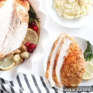 Sliced turkey breast on a plate next to a bowl of mashed potato and a whole turkey breast