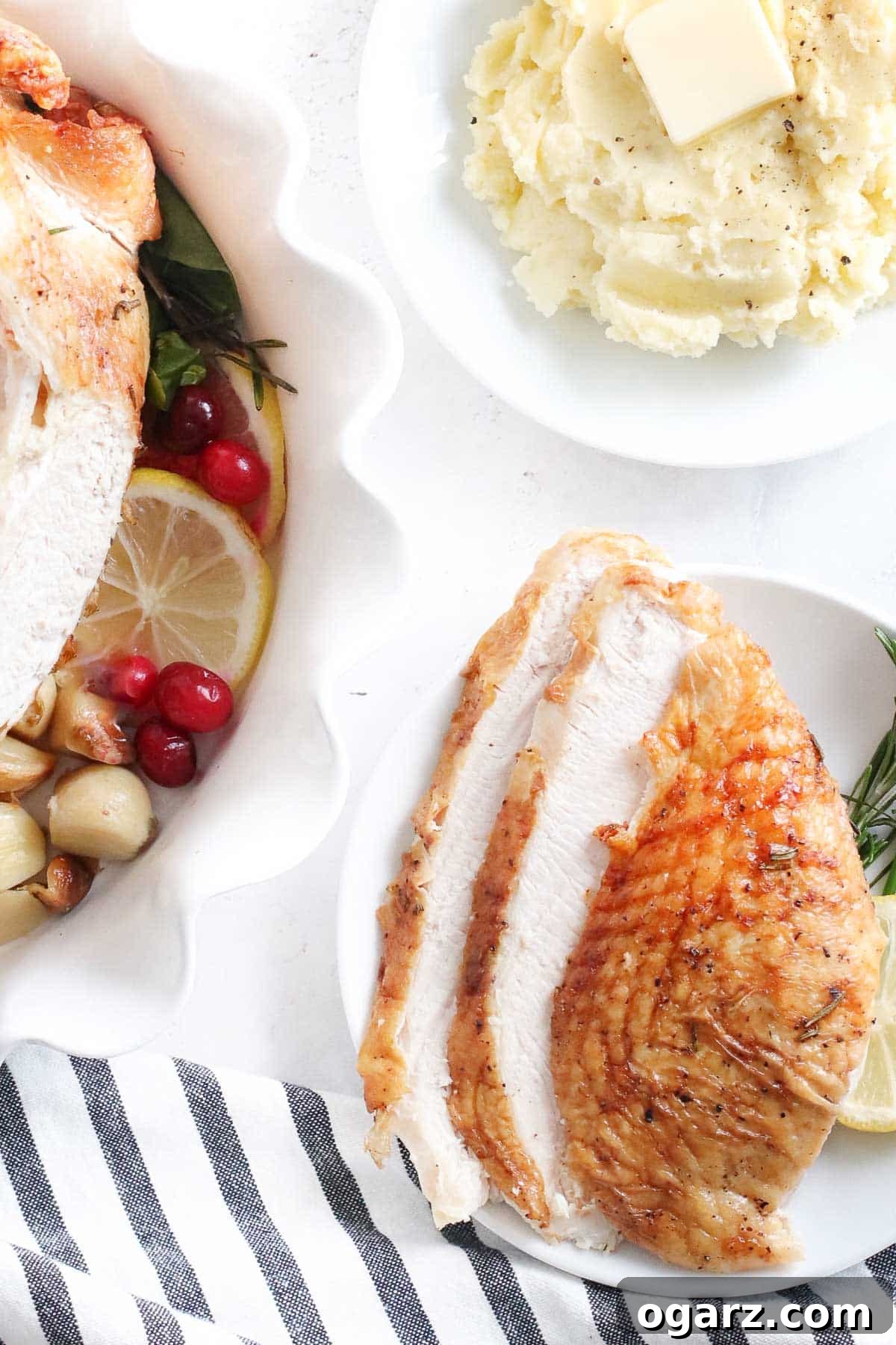 Crispy Air Fryer Turkey Breast 6 A platter featuring both a sliced turkey breast on a plate next to a bowl of creamy mashed potatoes, and a whole roasted turkey breast in the background