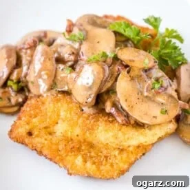 Schnitzel topped with Mushroom, bacon gravy, garnished with parsley