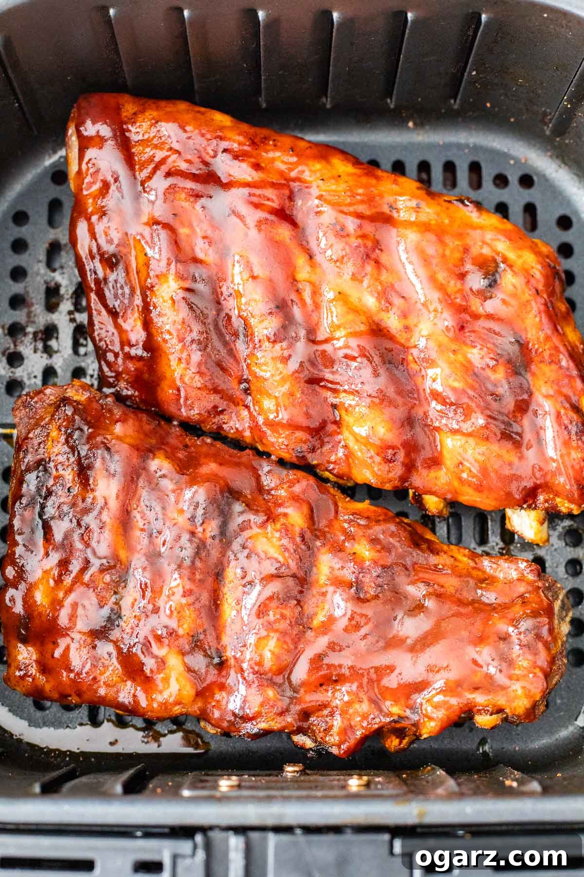 Perfect Air Fryer Ribs 5 A rack of ribs slathered with BBQ sauce in an air fryer basket.