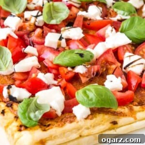 Close-up of tomato mozzarella puff pastry pizza with tomatoes, mozzarella, basil leaves and balsamic glaze.