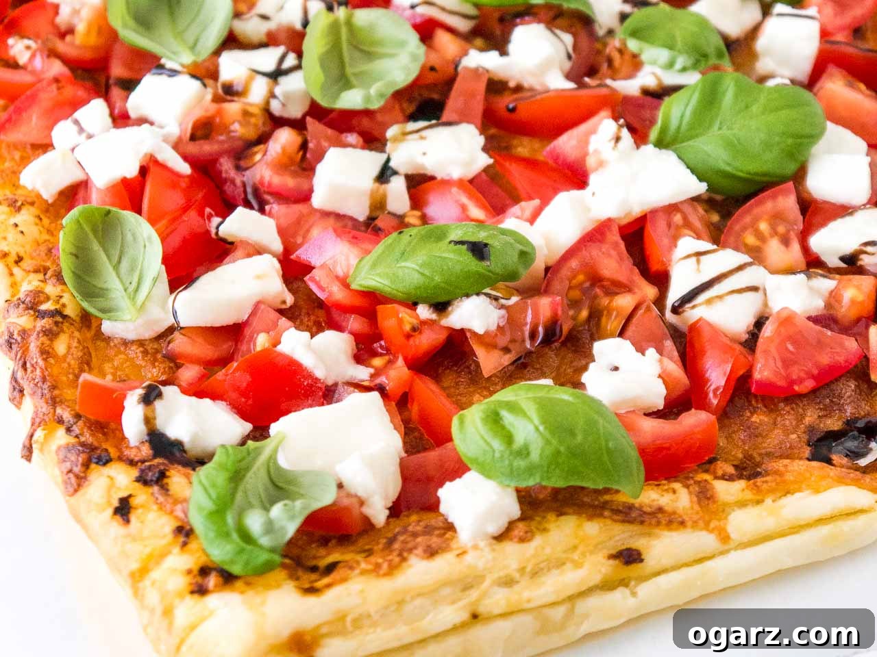 Puff Pastry Pizza with Fresh Tomato and Mozzarella 6 Close-up of a single slice of Tomato Mozzarella Puff Pastry Pizza, perfectly garnished with basil and balsamic glaze, ready to be enjoyed.