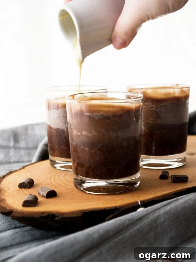 A close-up shot of the three-layered Copycat Lindor Truffle Chocolate Dessert in a clear glass, showing the brownie, the creamy filling, and the white chocolate topping.