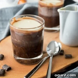A wooden cutting board with a glass of copycat Lindor truffle chocolate dessert on it next to some spoons.