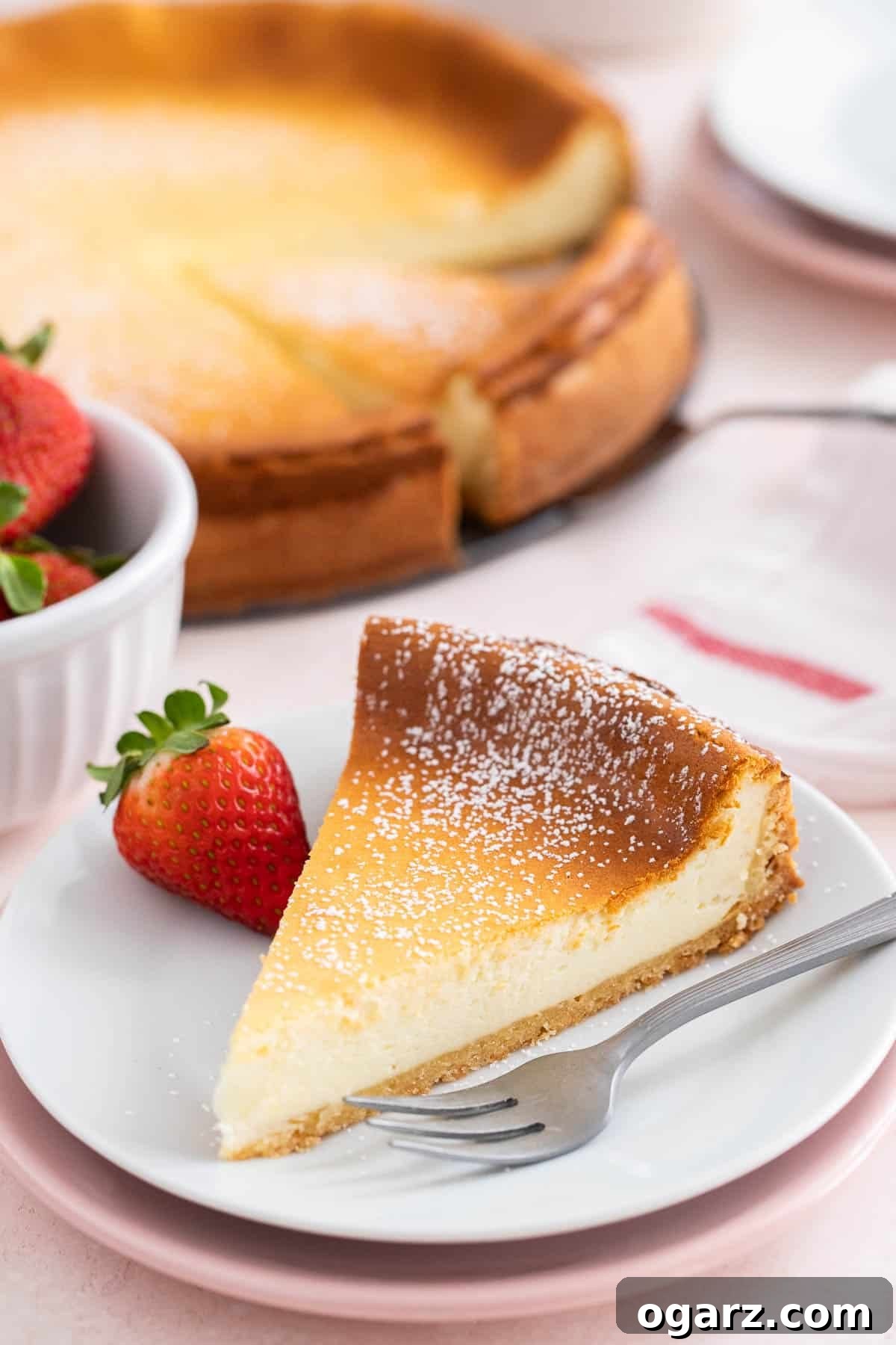Käsekuchen: The German Cheesecake 2 A perfectly baked slice of German cheesecake, or Käsekuchen, resting on a crisp white plate with a fork poised nearby, inviting a taste.