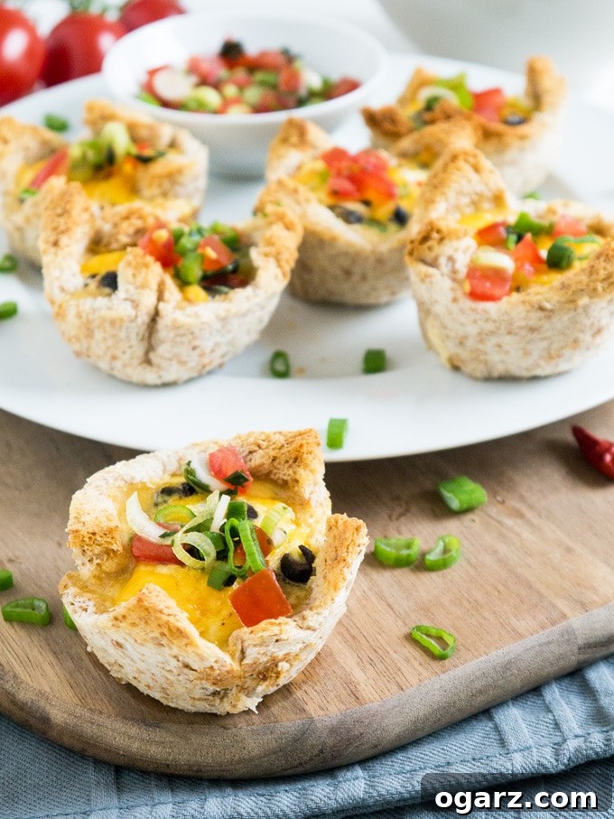 Mexican Fiesta Toast Bites 4 An array of Cheesy Mexican Toast Cups, garnished with fresh chives and cilantro, on a rustic wooden board.
