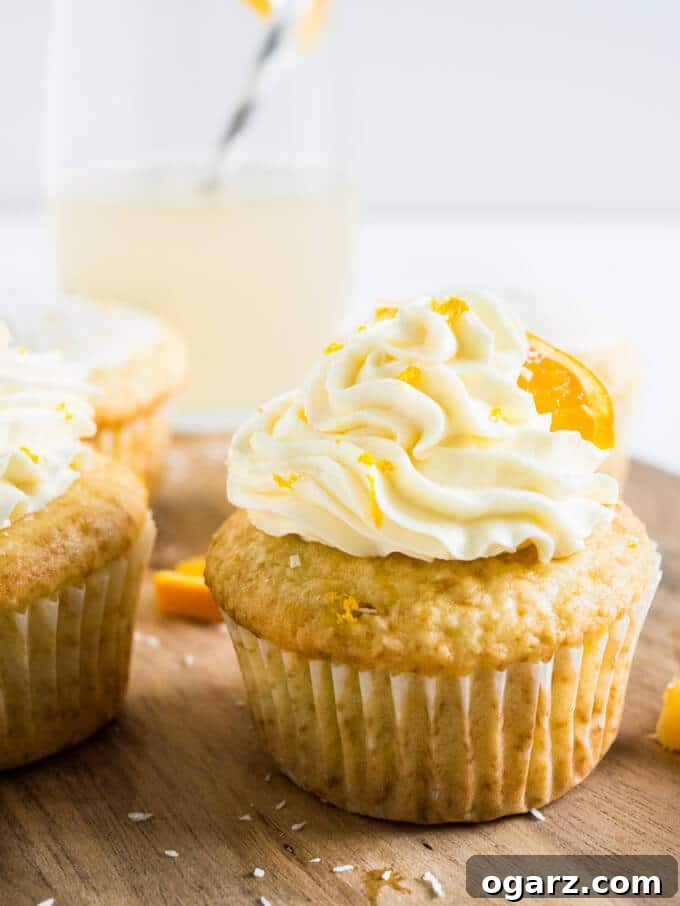 Nostalgic Orange Cream Cupcakes 5 Assortment of finished Orange Creamsicle Cupcakes, some with buttercream and some with a light glaze, on a rustic wooden board.