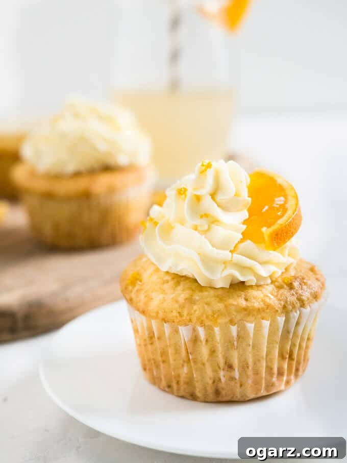 Nostalgic Orange Cream Cupcakes 6 A tray of freshly baked Orange Creamsicle Cupcakes, some frosted with buttercream and others with a smooth orange glaze.