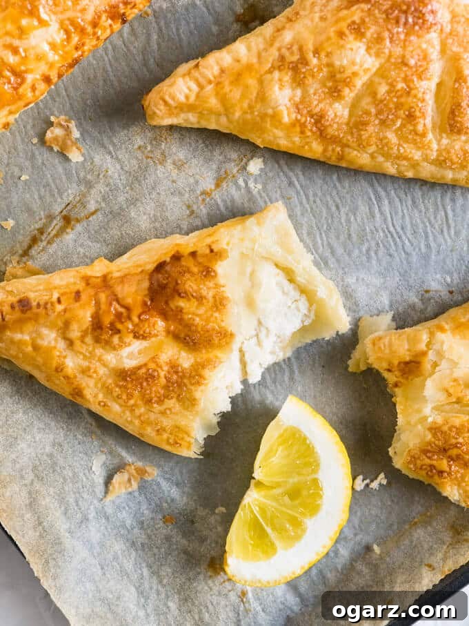 Zesty Lemon Puff Parcels 2 Crispy, golden-brown Lemon Puff Pastry Pockets filled with creamy lemon ricotta, garnished with powdered sugar.