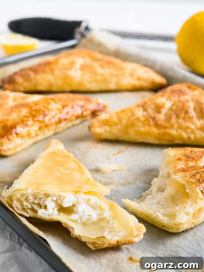Zesty Lemon Puff Parcels 4 Arrangement of baked Lemon Ricotta Puff Pastry Pockets on a white surface, ready to be served.