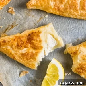 Lemon puff pastry pockets on white parchment with a wedge of lime.
