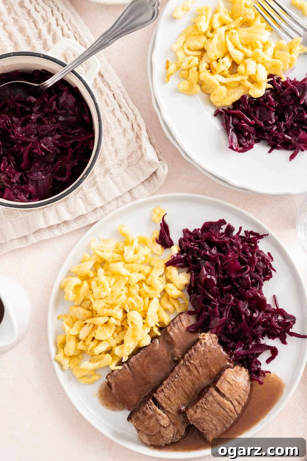 Tangy German Pot Roast 4 A sliced roast served on a white plate with Blaukraut in a serving dish next to it.