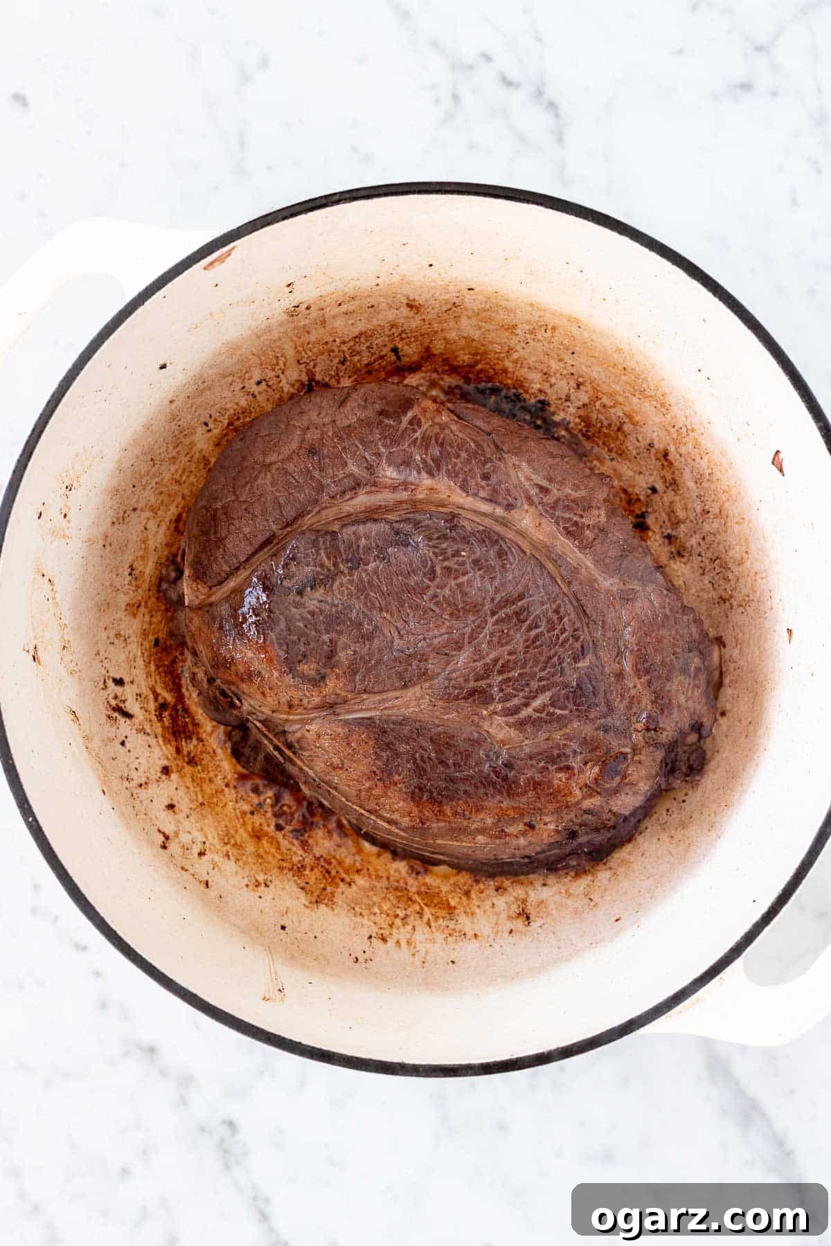 Tangy German Pot Roast 9 Seared roast in a white Dutch oven.