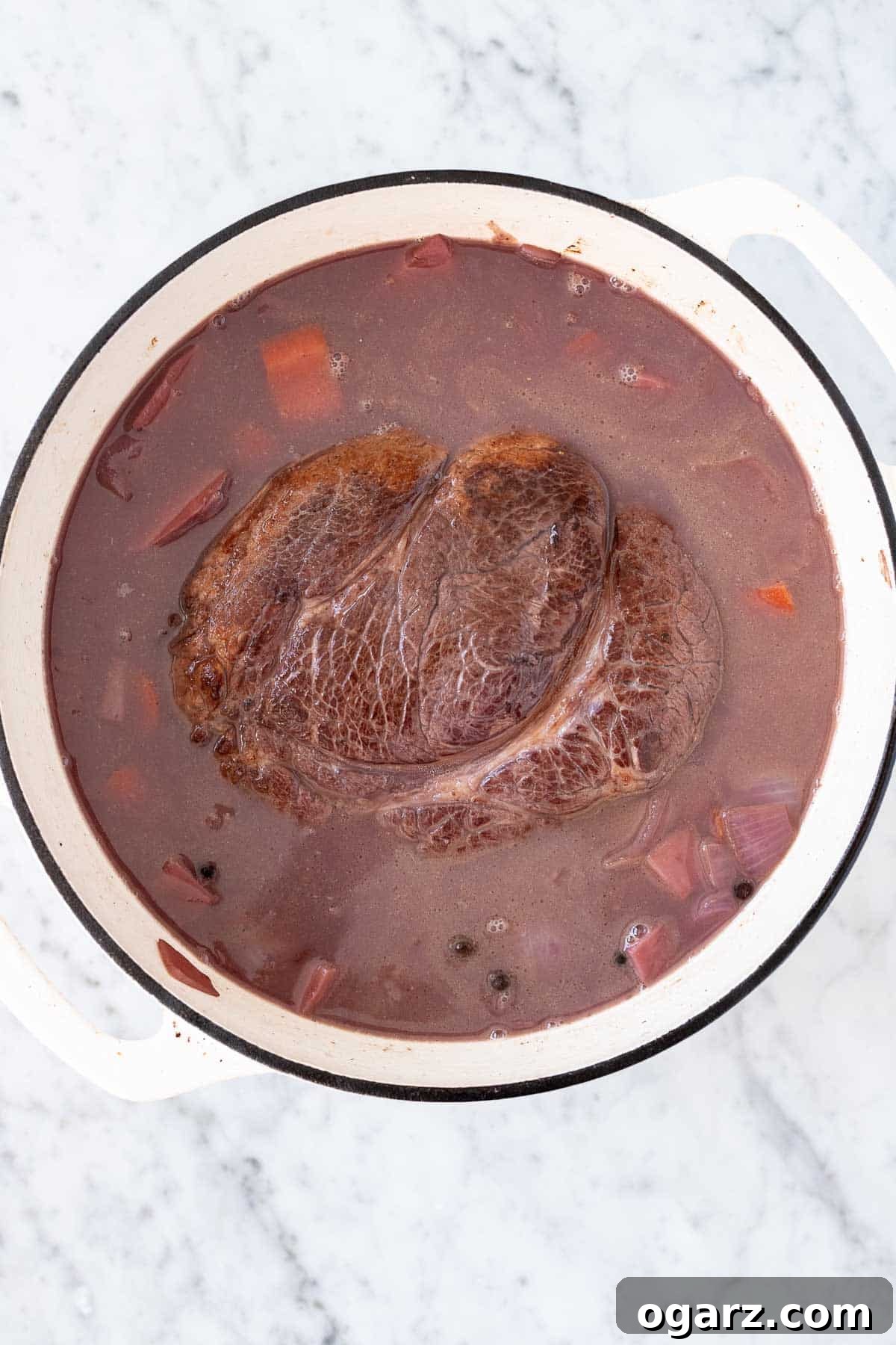 Tangy German Pot Roast 10 Roast, brine, and vegetables in a white dutch oven.