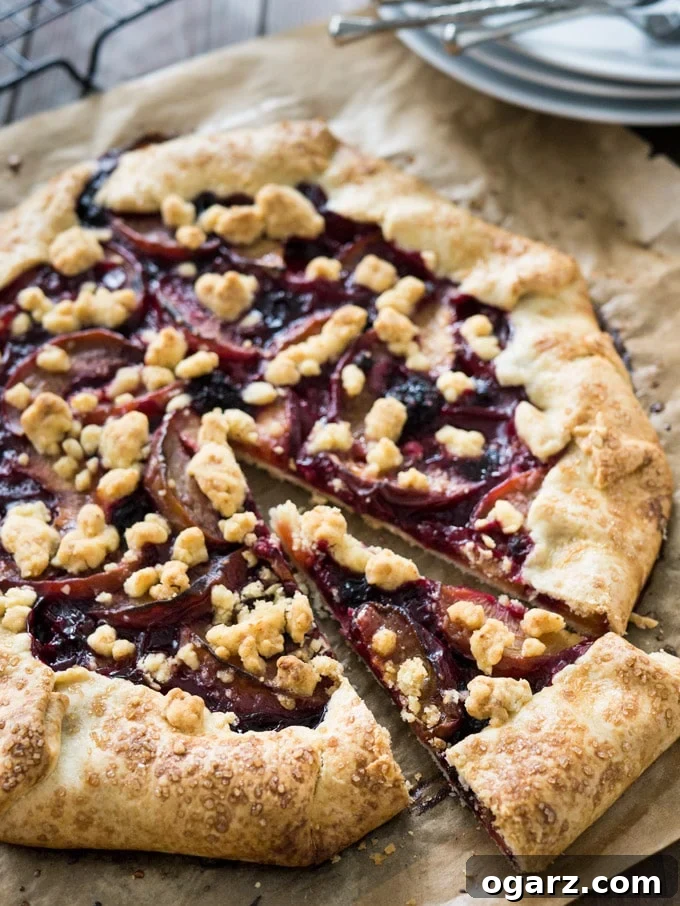 A freshly baked Peach and Berry Crostata with a slice cut out, served on a wooden board with a scoop of vanilla ice cream, ready to be enjoyed.