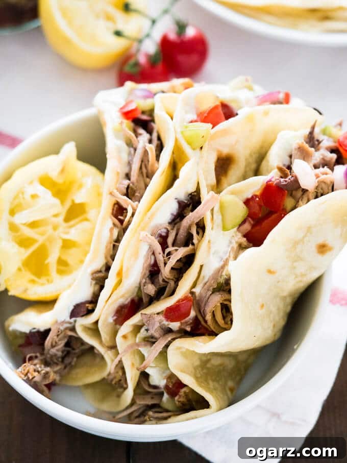 Delicious Greek Tacos with homemade Tzatziki, slow cooker pulled pork Gyros and Greek salsa. Served on homemade flour tortillas! A great twist on normal tacos!