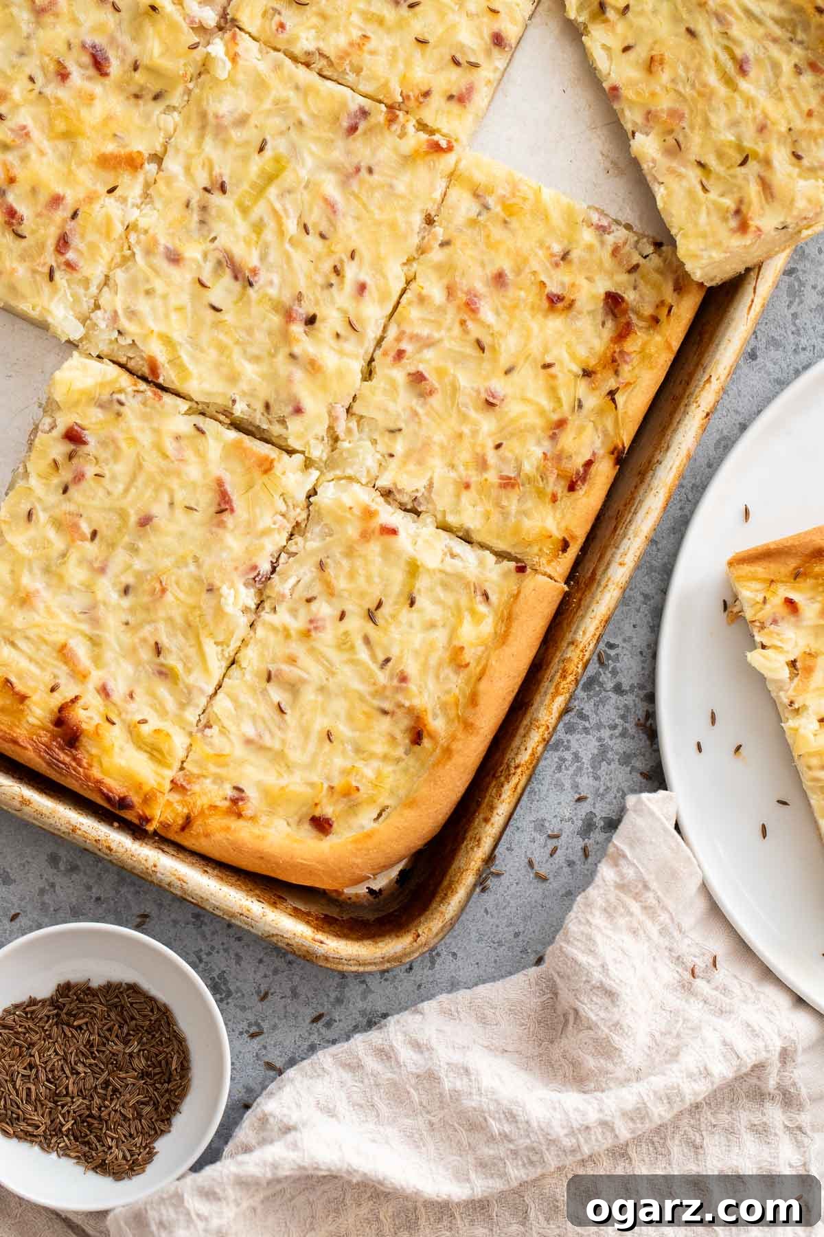 Zwiebelkuchen on a plate and on a baking sheet, ready to be served.