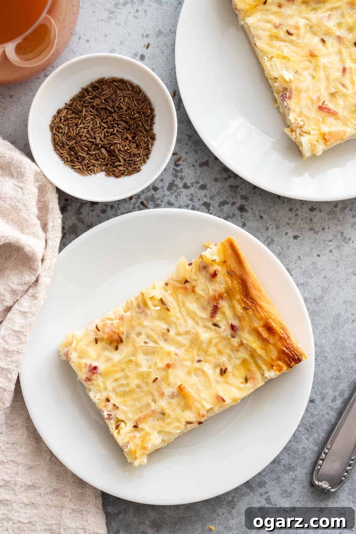 A slice of Zwiebelkuchen on a white plate, showcasing the rich onion and bacon topping.