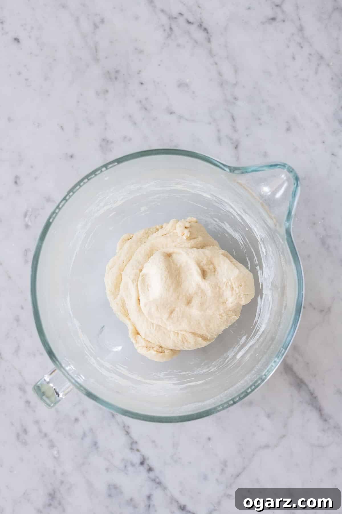 Yeast dough in a glass bowl, ready for rising.