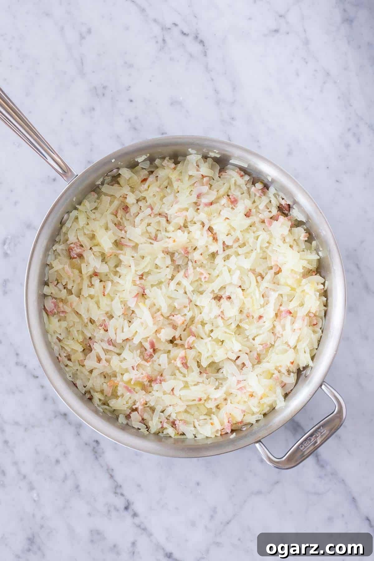 Onion and bacon mixture cooking in a large skillet.
