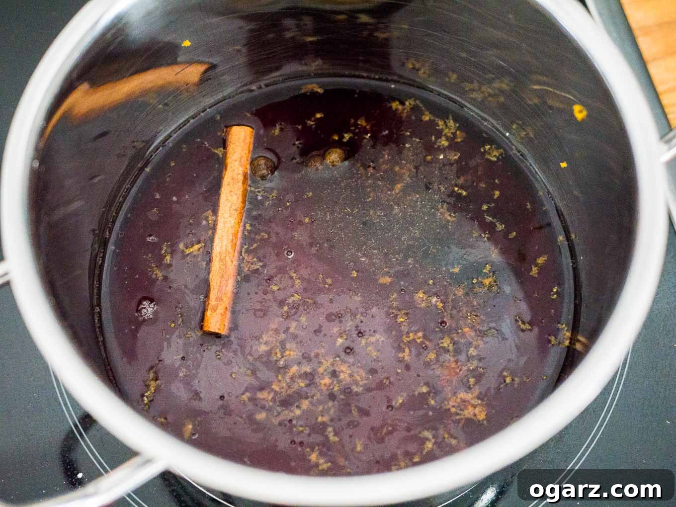 Ingredients for mulled wine liqueur, including red wine, rum, spices, and orange slices, laid out for preparation.