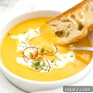Creamy Instant Pot Carrot Soup 8 A bowl of carrot soup with sour cream and chili threads with a toasted slice of bread and a spoon in it.