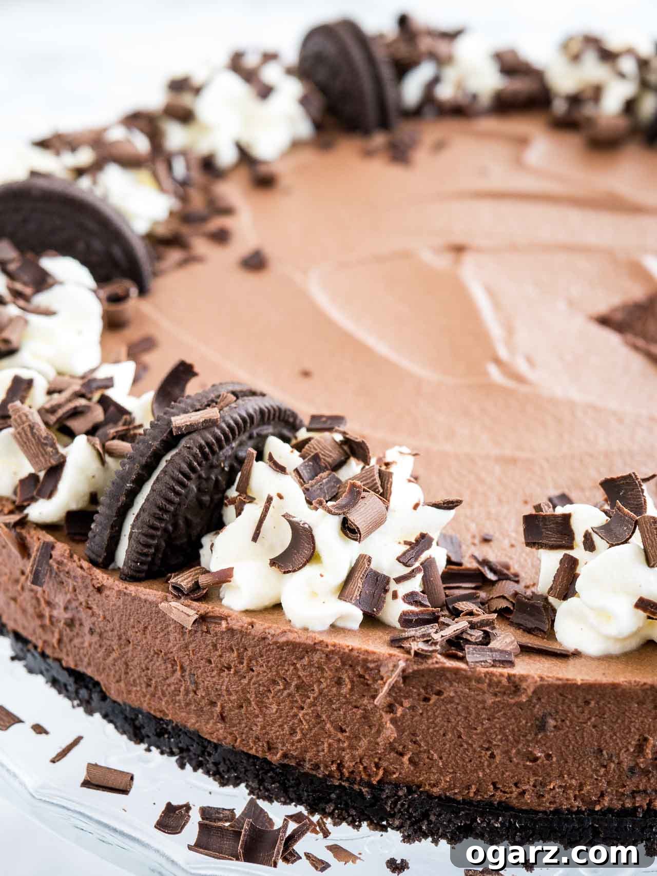 Decadent Chocolate Mousse Dream 4 Close-up of chocolate mousse cake with Oreo crust, topped with halved Oreo cookies, whipped cream and chocolate shavings.