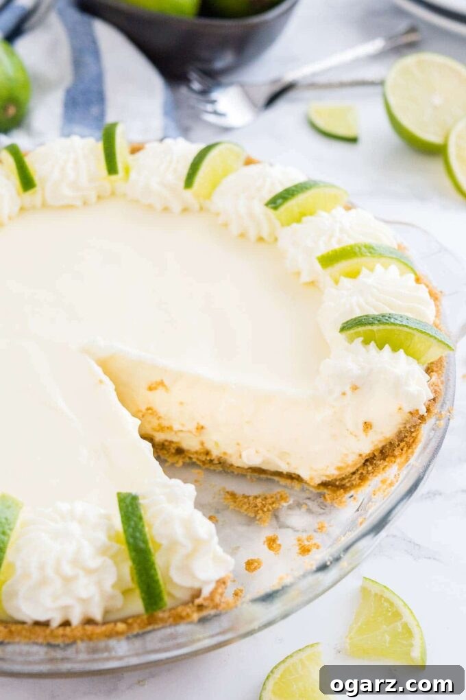Tangy No-Bake Key Lime Pie 4 A No-Bake Key Lime Pie with one slice removed, revealing its thick, creamy filling and golden graham cracker crust.