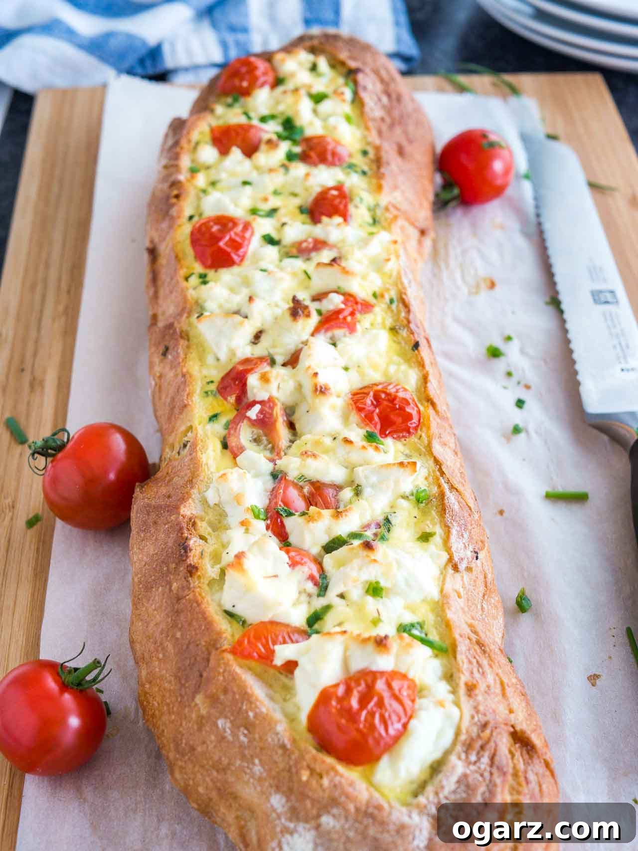 Whole Tomato Feta Stuffed French Bread with fresh garnishes, perfect for a gathering.