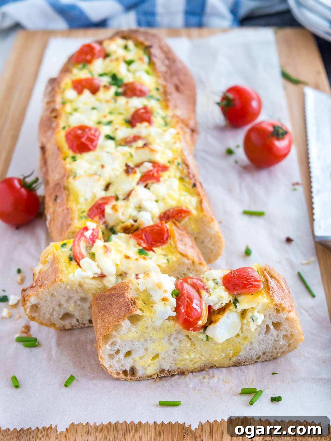 Freshly cut slices of Tomato Feta Stuffed French Bread next to the loaf.