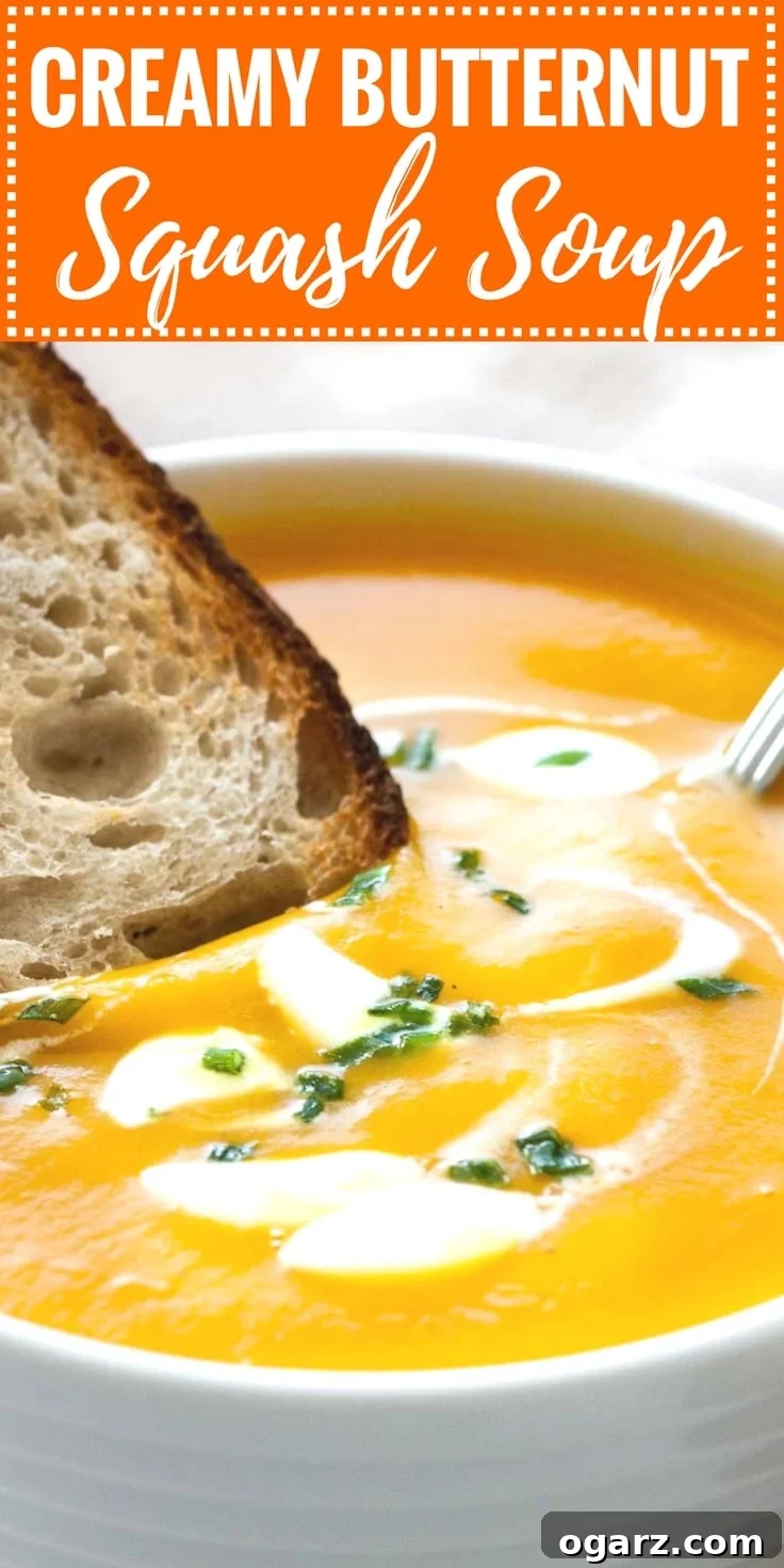 Silken Butternut Squash Delight 7 Image with text: Creamy butternut squash soup. Image: Close-up of a white bowl with butternut squash soup, with dollops of sour cream and chives, a spoon in it and a toasted slice of bread.