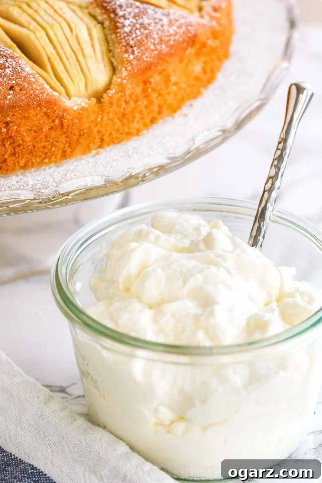 Whipped Cream in a glass jar with a spoon, ready to be served with apple cake.