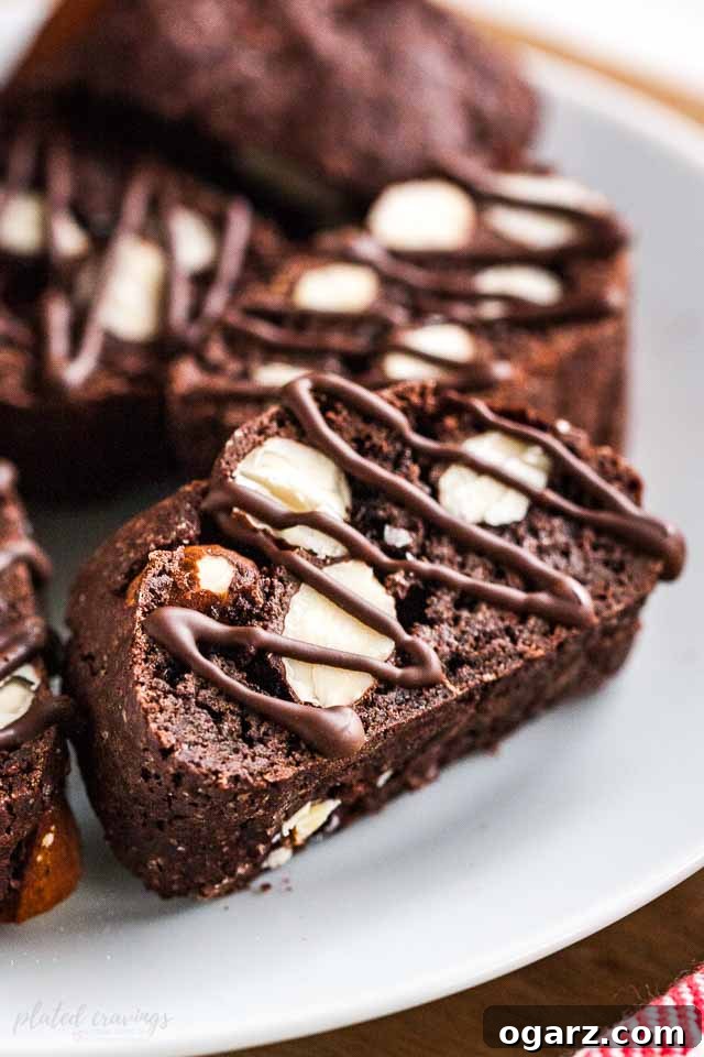 Several pieces of chocolate almond biscotti on a white plate.