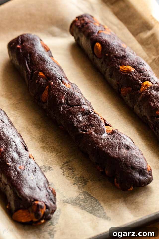 3 logs of chocolate biscotti dough on parchment paper.