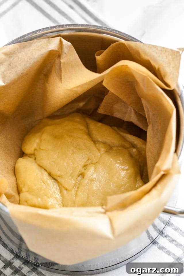 A pot lined with parchment paper containing the doughball for the apple strudel.