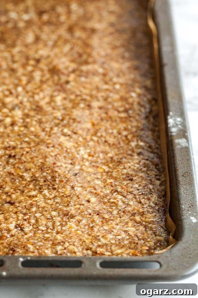 A baking pan, lined with parchment paper, showcasing the freshly baked and caramelized nut topping, golden and ready for cooling and cutting.