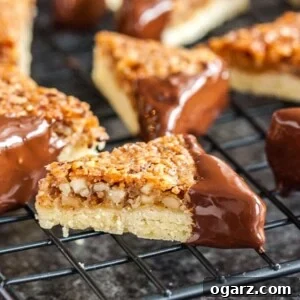 Nut corners with one chocolate-dipped corner on a black cooling rack over a dark surface.