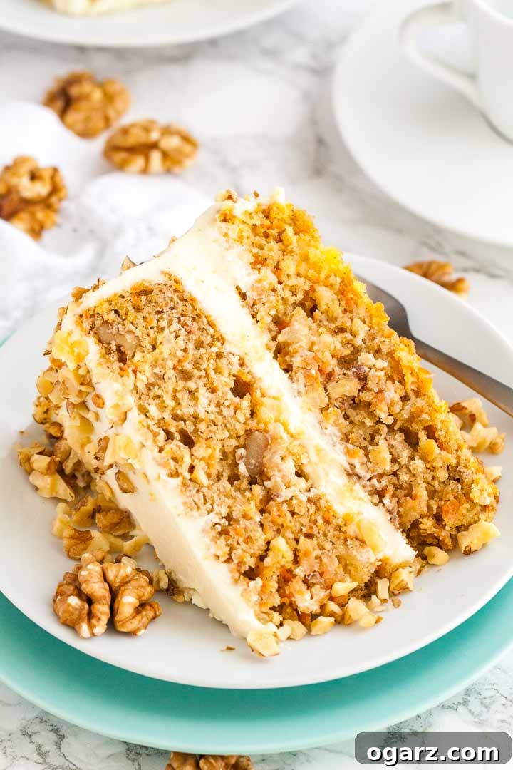 Experience the best moist carrot pineapple cake, easily made from scratch, layered with a delectable cream cheese frosting. #carrotcake #pineapplecake #homemadecake #creamcheesefrosting #easybaking A slice of carrot pineapple cake garnished with walnuts on a white plate.