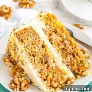 A slice of carrot pineapple cake garnished with walnuts lying on its side on a white plate stacked on a teal plate with a fork.