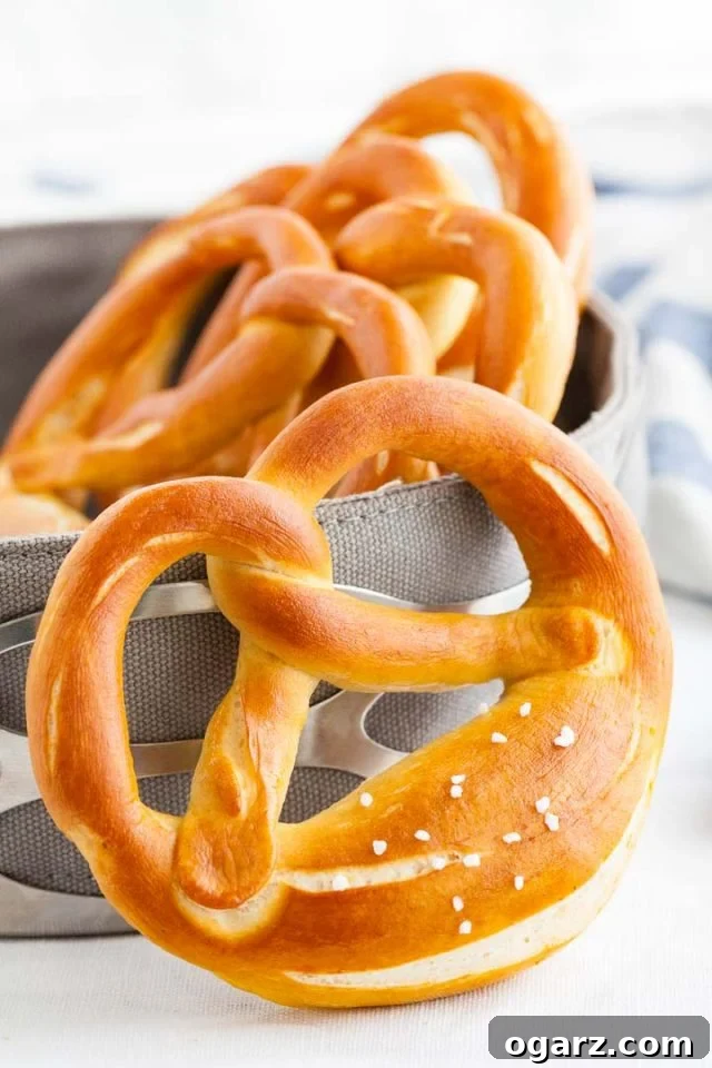 Hearty Bavarian Knots 2 Several golden brown Bavarian pretzels in a basket with a blue and white checkered towel.