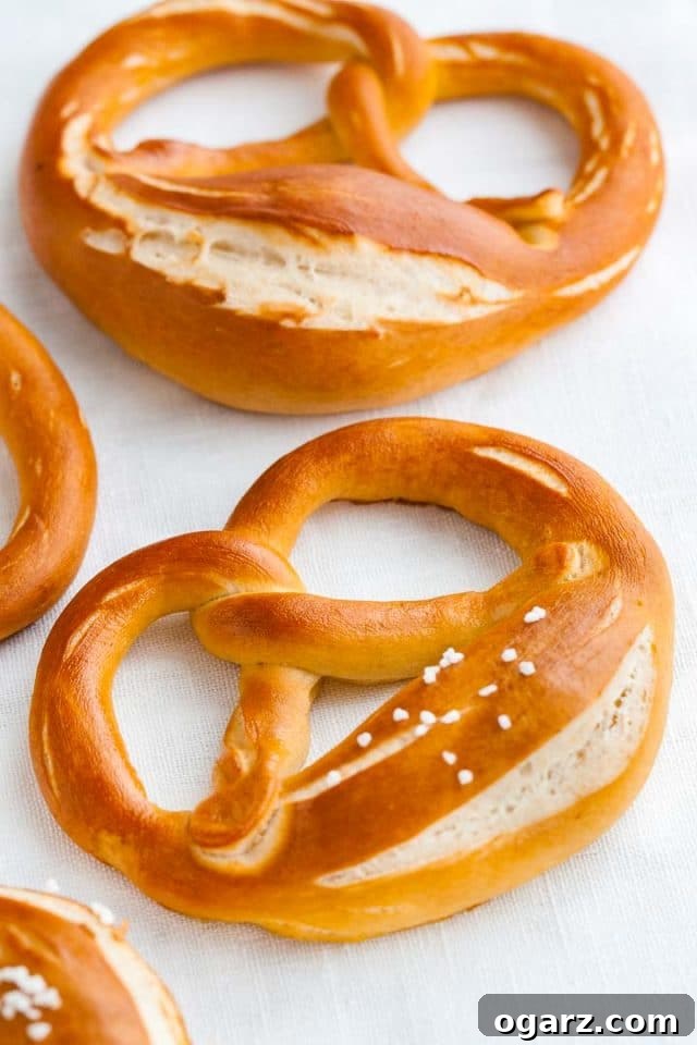 Hearty Bavarian Knots 3 Three freshly baked Bavarian pretzels on parchment paper, ready to be enjoyed.