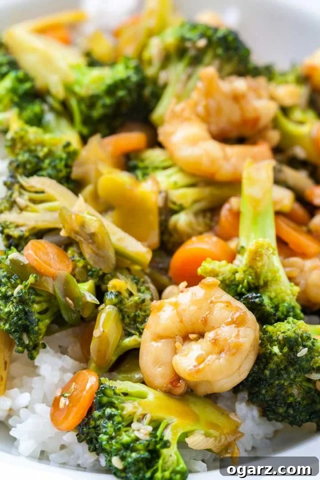 Sticky Honey Garlic Shrimp with Roasted Broccoli 3 Close-up of a plate of rice topped with shrimp and broccoli stir fry, showing the vibrant colors.