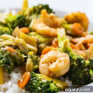 A plate of rice topped with shrimp and broccoli stir fry.