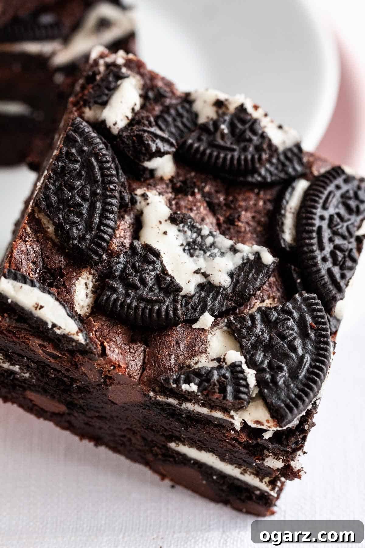 Decadent Oreo Fudge Brownies 4 A brownie with Oreo cookies on top leaning against a plate.