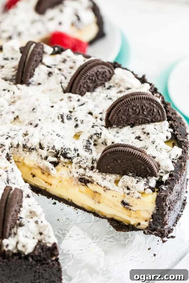 Oreo banana cream cake with a slice missing on a glass serving dish.