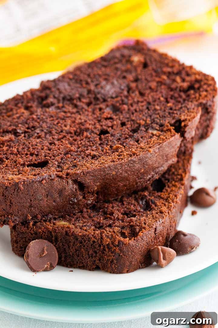 Decadent Chocolate Banana Bread 4 Two generous slices of rich chocolate banana bread, stacked and garnished with chocolate chips, with a fresh banana in the background.
