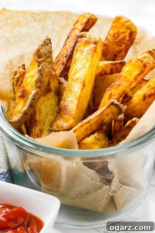 Perfectly Crispy Air Fryer French Fries in a jar A charming glass jar, lined with parchment paper, holding a serving of brown, exceptionally crispy Air Fryer French Fries, ready to be enjoyed.