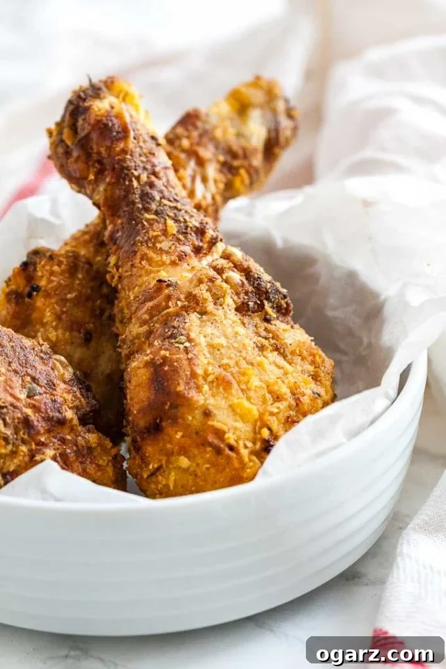 Golden Crispy Air Fryer Chicken 2 Crispy breaded chicken drumsticks served in a white bowl lined with parchment paper